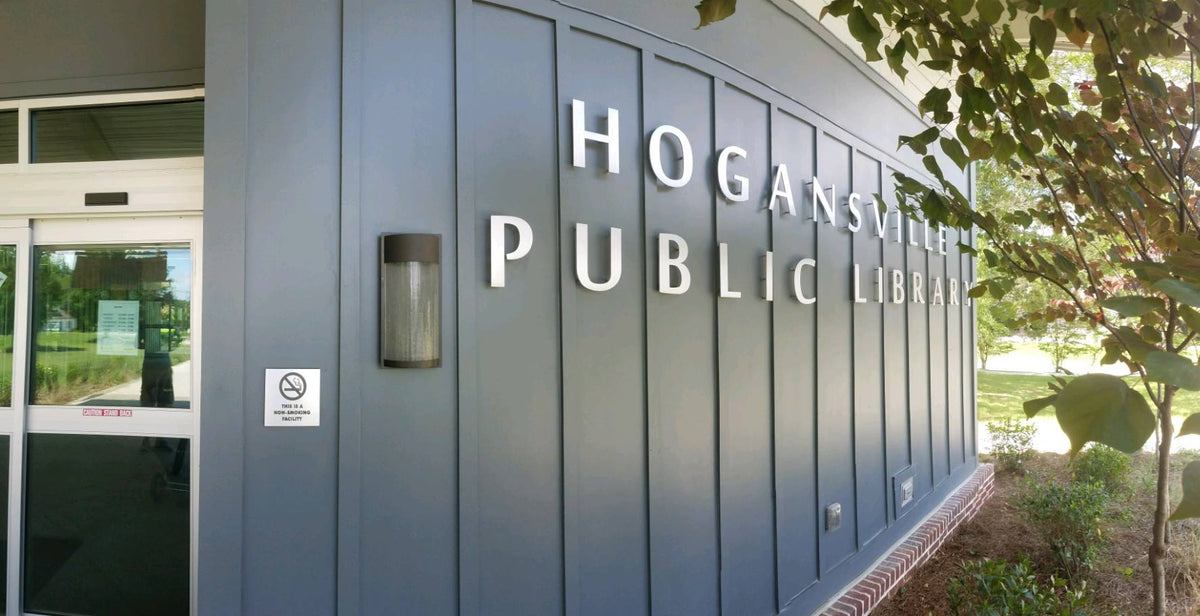 Exterior dimensional letters identifying Hogansville Public Library, mounted on the building's gray architectural facade.